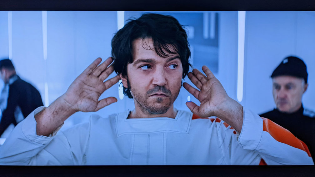 AndorS01E08_18 Cassian Andor in Narkina 5 prison scrubs, hands moving away from his head, looking shifty